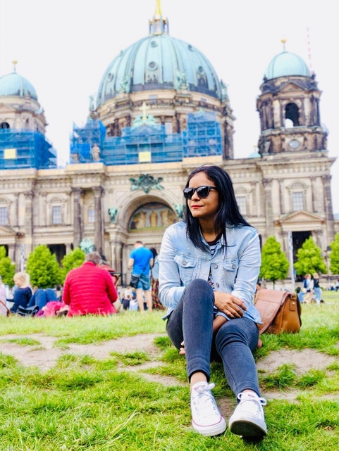 Female software developer sitting in the grass in front of the famous Berliner Dom in her new home city.